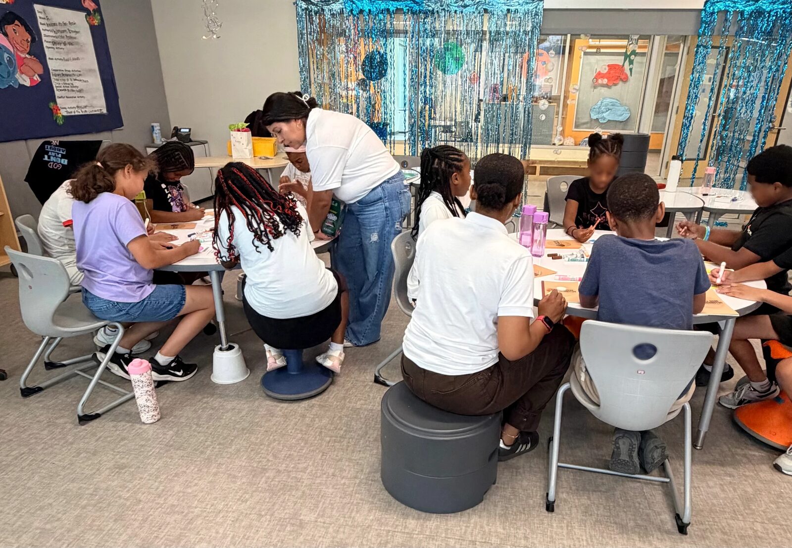 Students working on an activity at tables while a mentor helps during an AOAUS session